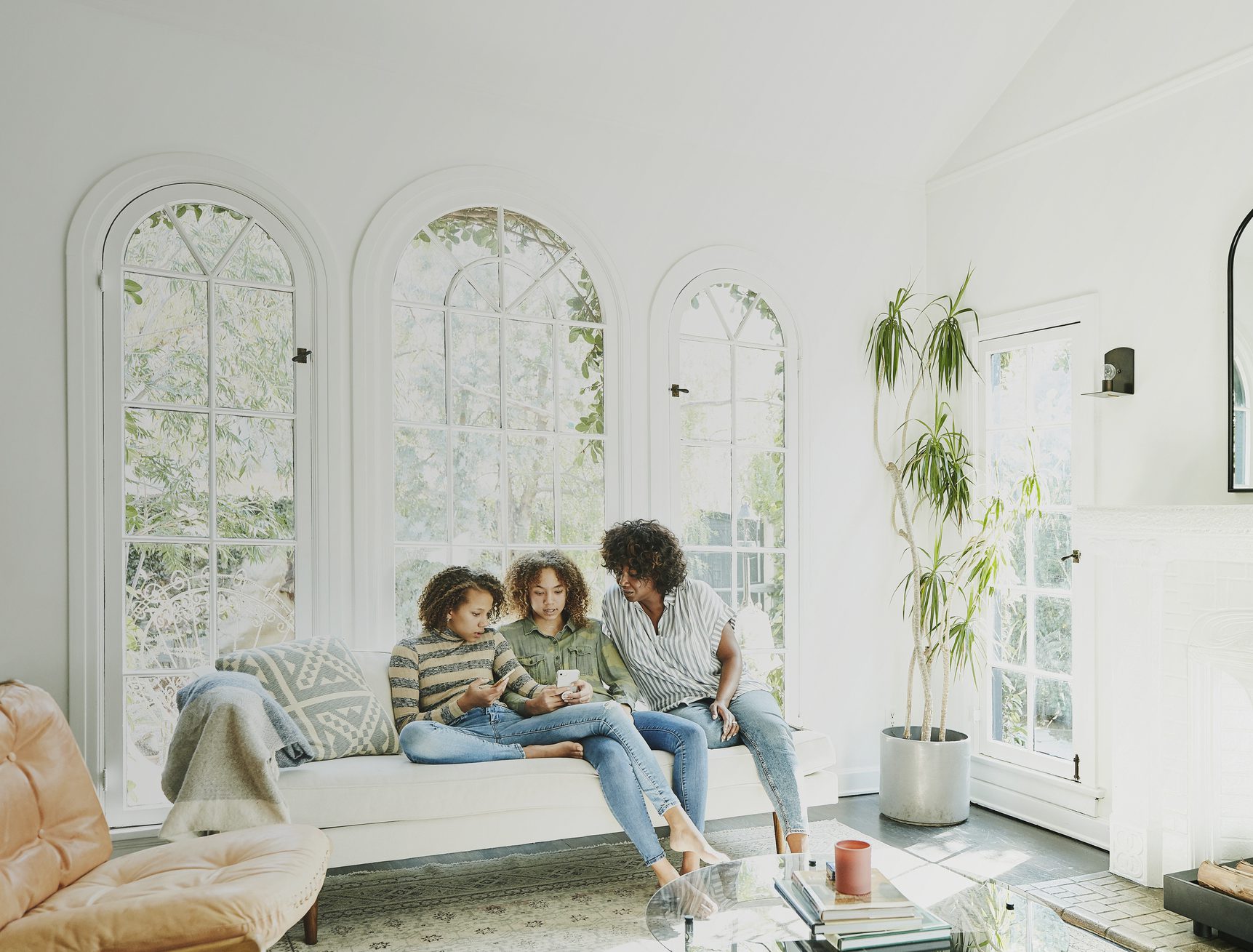 Mother and daughters sitting in living room watching video on smart phone